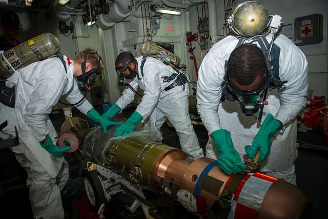 Navy personnel in protective gear working with specialized equipment